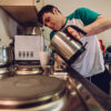 Quadriplegic young adult pouring himself a cup of tea using the kettle.